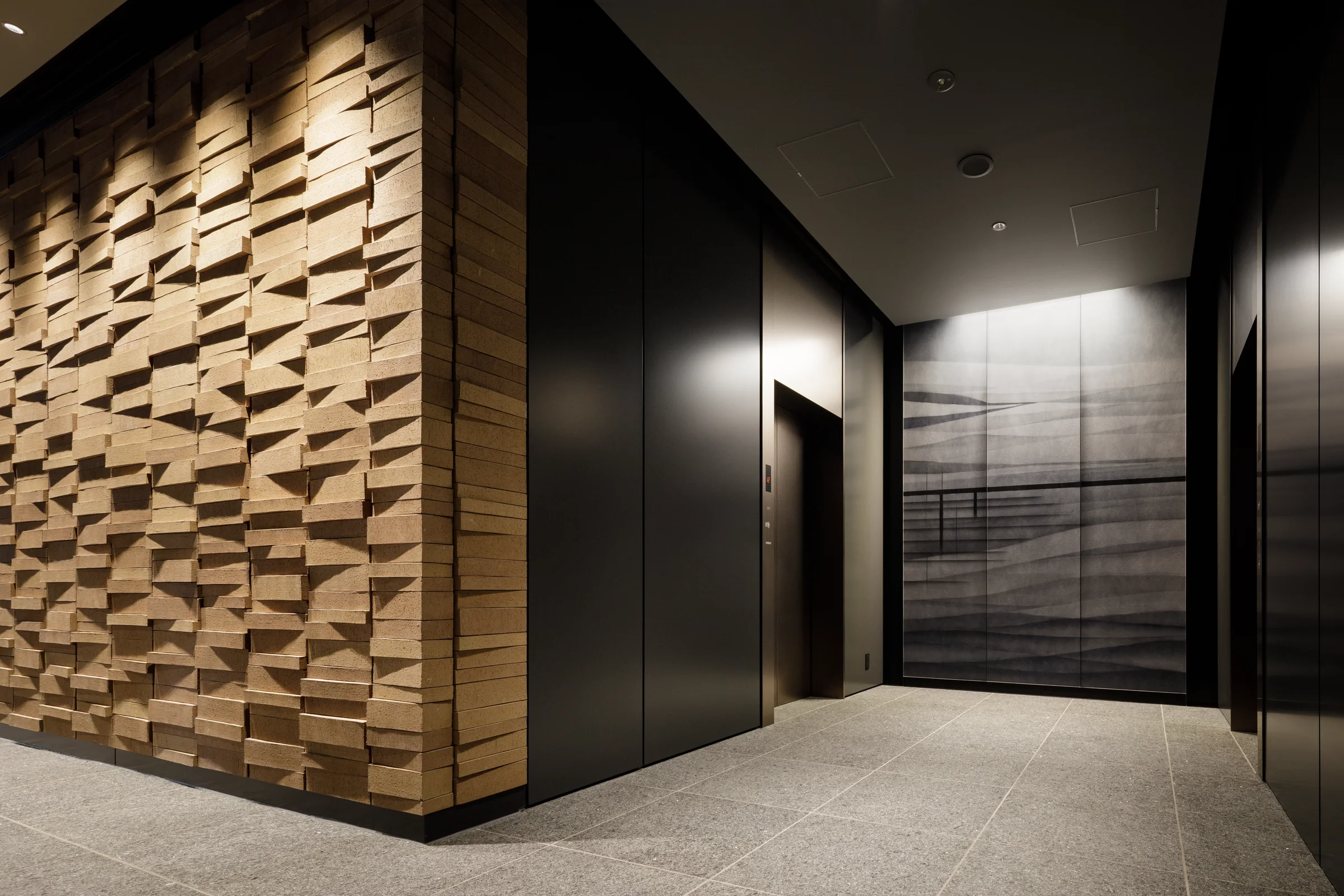 Sculptural folded washi wall beside a dark stone and timber office entrance