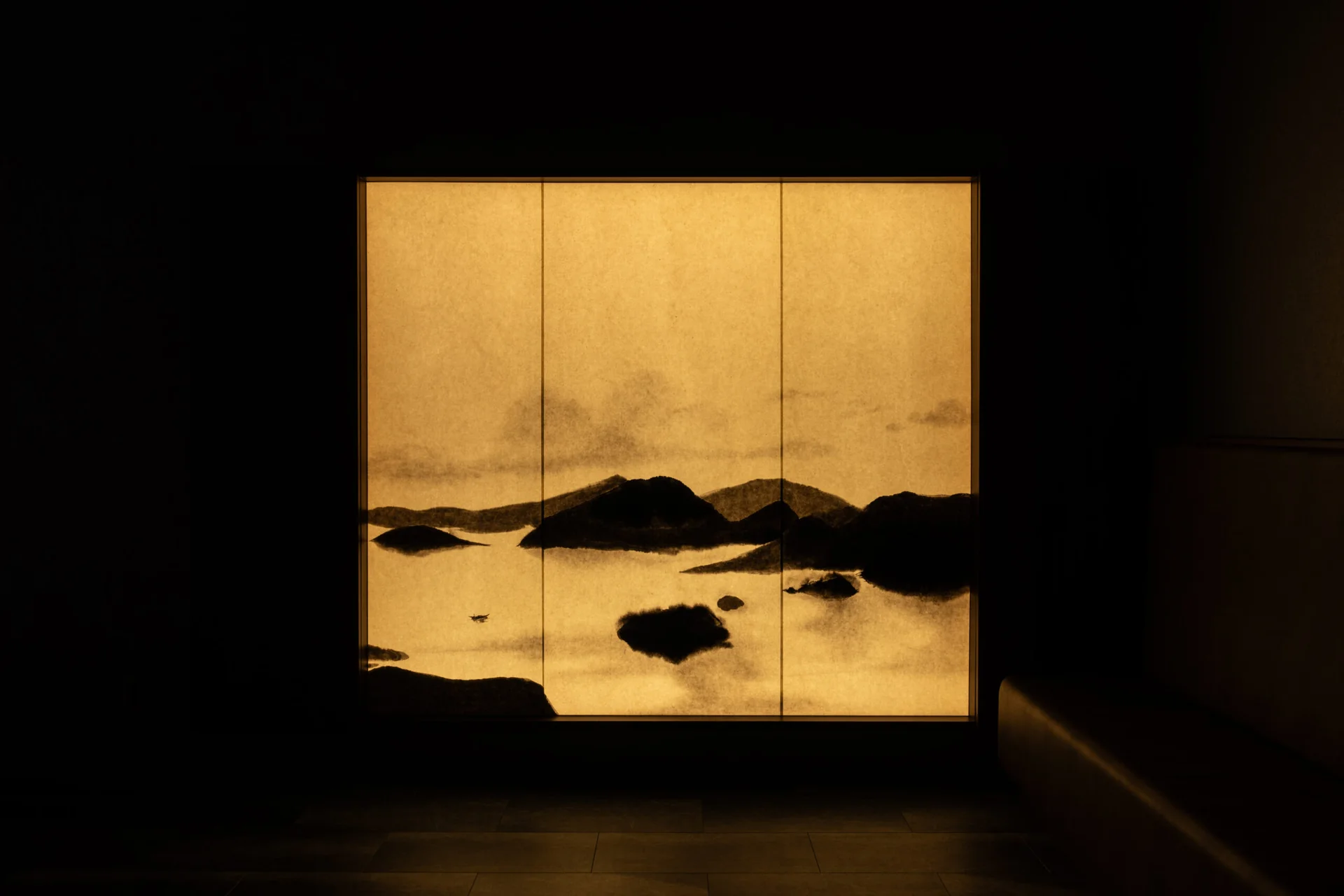 Illuminated washi art panel depicting a dark landscape against a gold field
